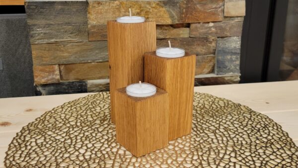 Three tealight candle holders made from solid oak rectangles of different sizes. A tealight sits in placement holes on the tops.