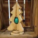 A rustic, simple wood christmas tree on a stand, with a green ornament inside the tree.