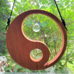 A suncatcher, shaped in the fashion of Yin Yang, hangs in a window.