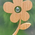 Wood flower with a glass prism ball suspended in the middle of the blossom, hanging in a window.