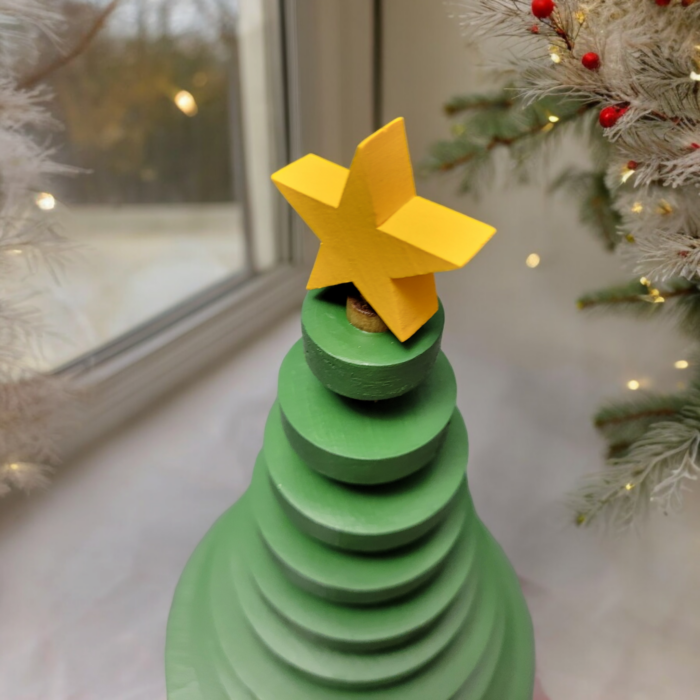 Ornamental wood christmas tree made from wood discs, decreasing in size up to the top. A yellow star adorns the tree.