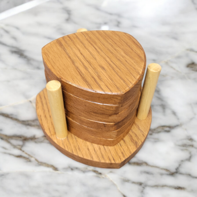 Six solid oak coasters with a holder sitting on a table top.