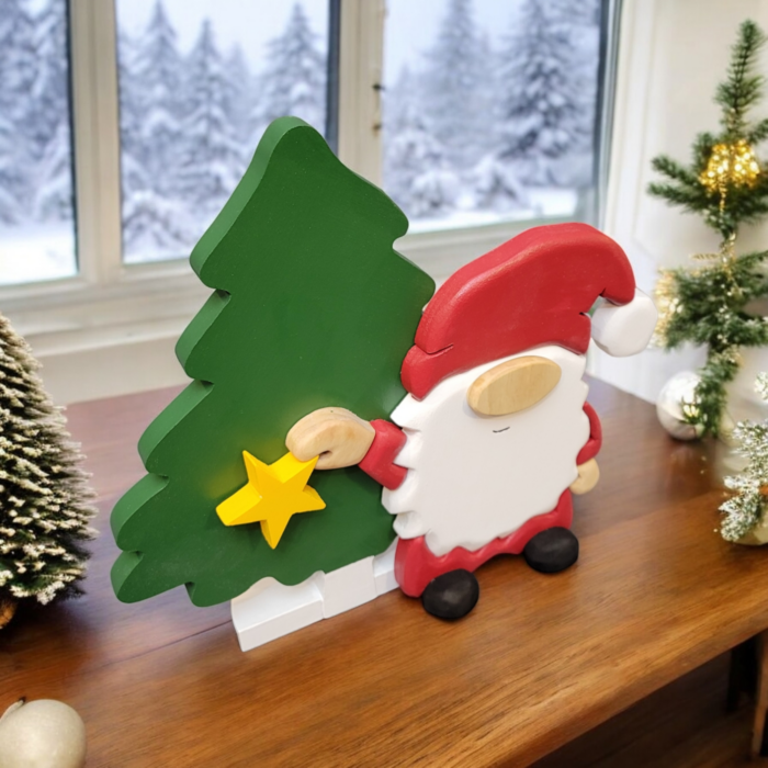 Christmas gnome with while beard, red hat, holding a yellow star, standing in front of a tall green tree.