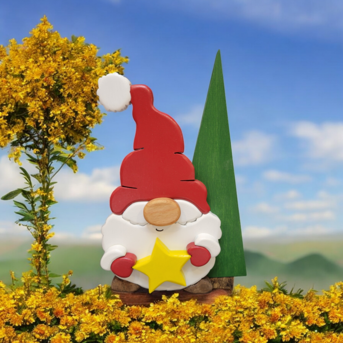 Christmas gnome with while beard, red hat and gloves, holding a yellow star, standing in front of a tall green tree.