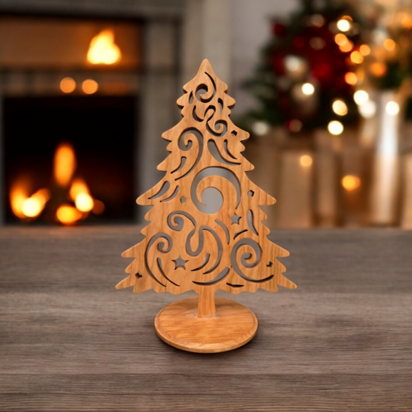 A delicate and intricately cut christmas tree sits on a table. The tree has curves and swirls cut into it, giving it a look of swirling wind.