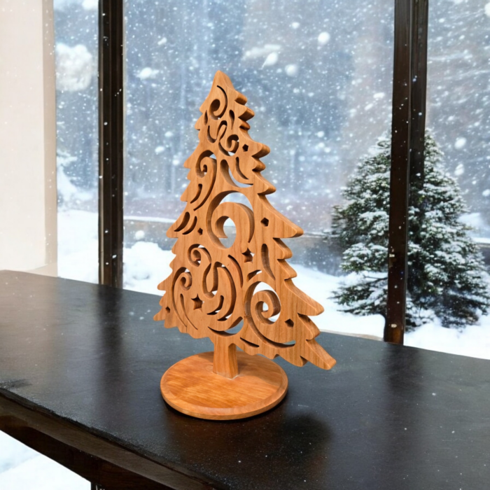 A delicate and intricately cut christmas tree sits on a table. The tree has curves and swirls cut into it, giving it a look of swirling wind.