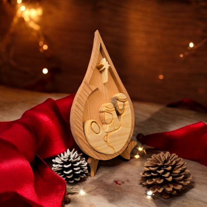 A christmas scene of ornaments and lights, with a wood teardrop shaped centerpiece depicting the Holy Family under the Star.