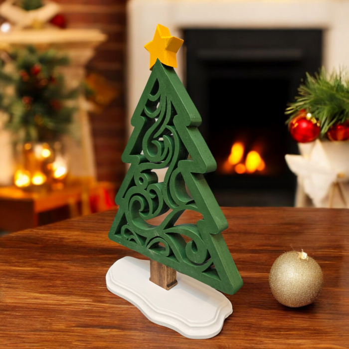 A delicate, ornamental wood tree, with a simple triangle-like outline and intricate swirl cuts on the inside. The tree stands on a white base with a yellow star on top.