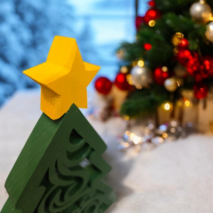 The yellow star on top of a green swirly cut ornamental christmas tree.