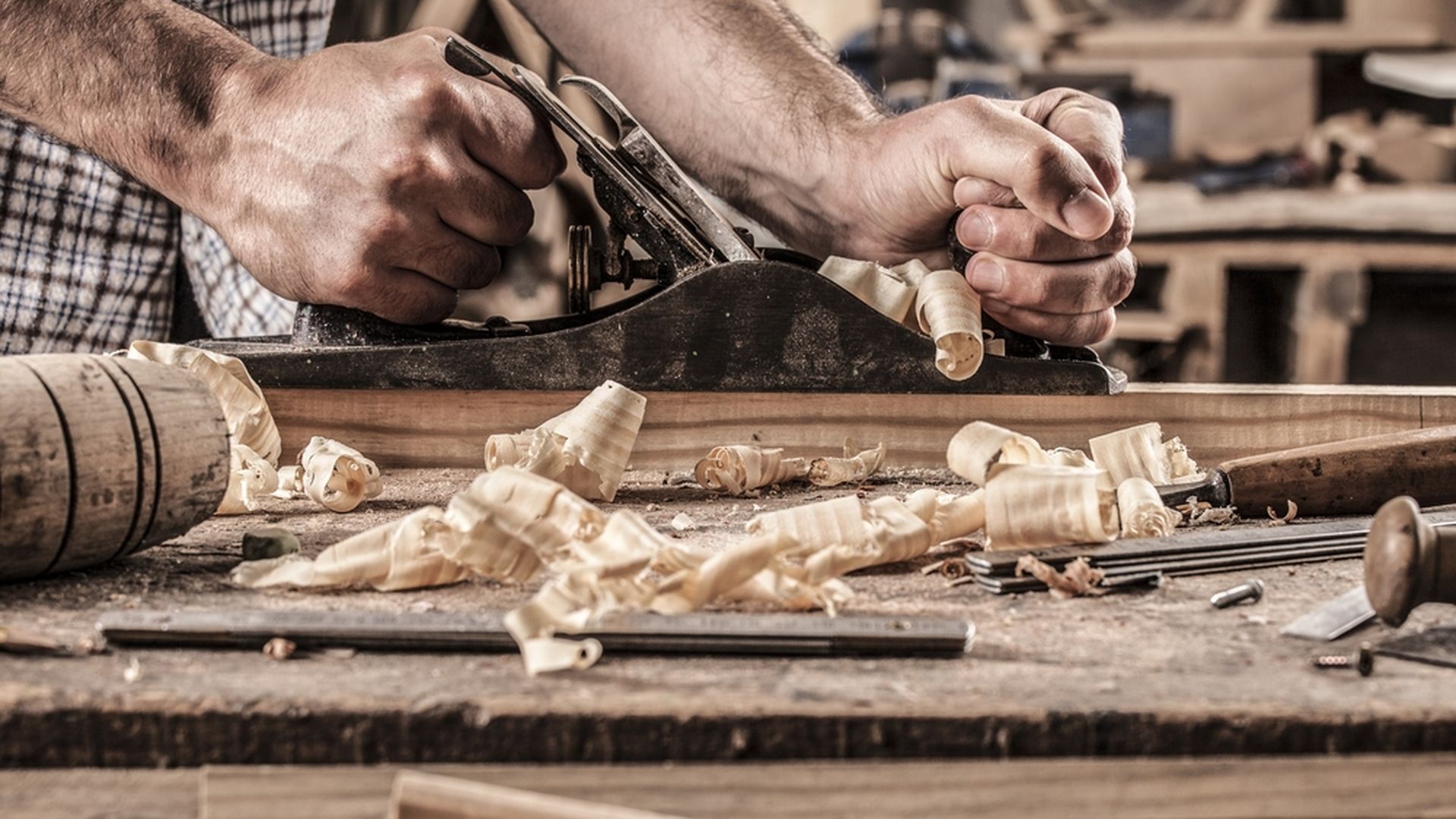 Photo of a carpenter's hands, using a wood planer.