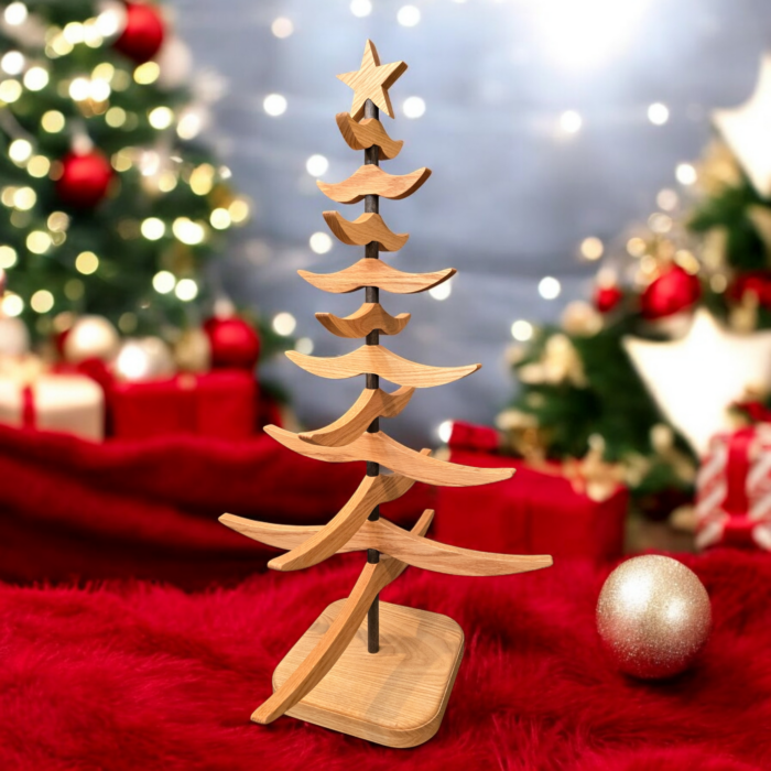 Wooden tree sitting on a red fabric, surrounded by Christmas decorations.