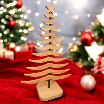 Wooden tree sitting on a red fabric, surrounded by Christmas decorations.