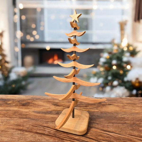 Wooden tree sitting on a brown wood table, with Christmas decorations in the background.