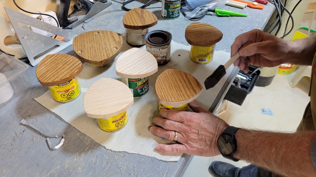 Coasters laid out on workbench, finished with an oak stain and polyurethane.