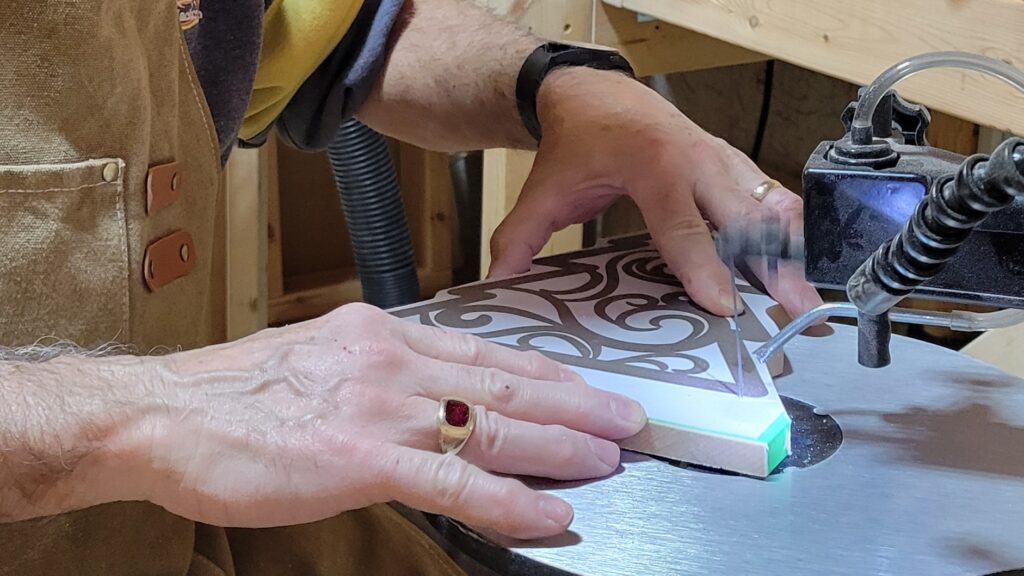 Photo of a small Christmas tree being cut out of a piece of wood.