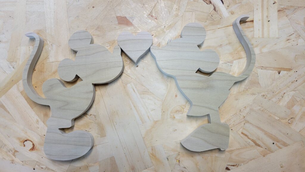 Mickey and Minnie mouse, cut out and lying on a wood surface, in preparation to become bookends.