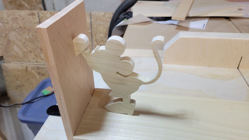 A wood cutout of Minnie Mouse, facing the upright side of a bookend.