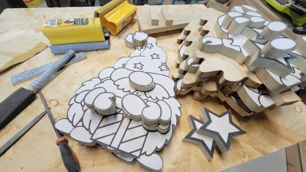 A workbench with multiple gnome figures, cutout and ready to be sanded and shaped