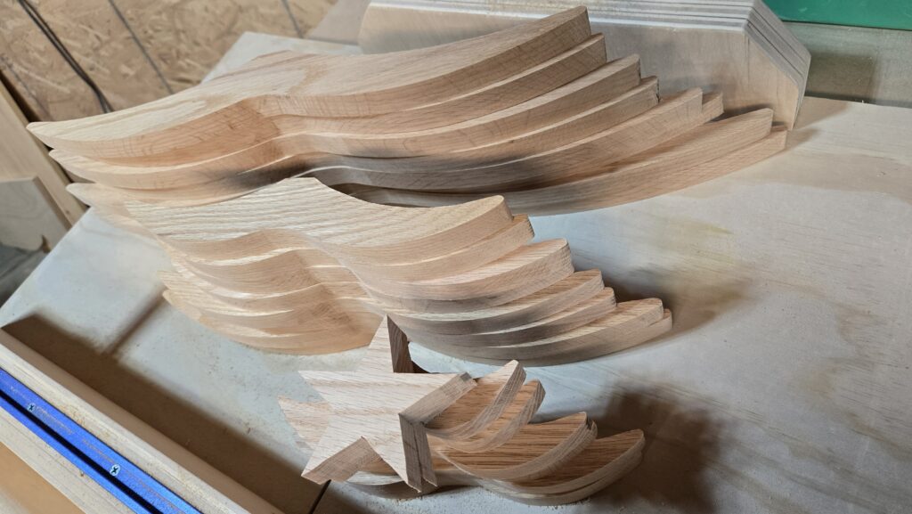 Twenty-two wooden tree branches and two stars are lying on a table, cut out, ready for sanding and shaping.