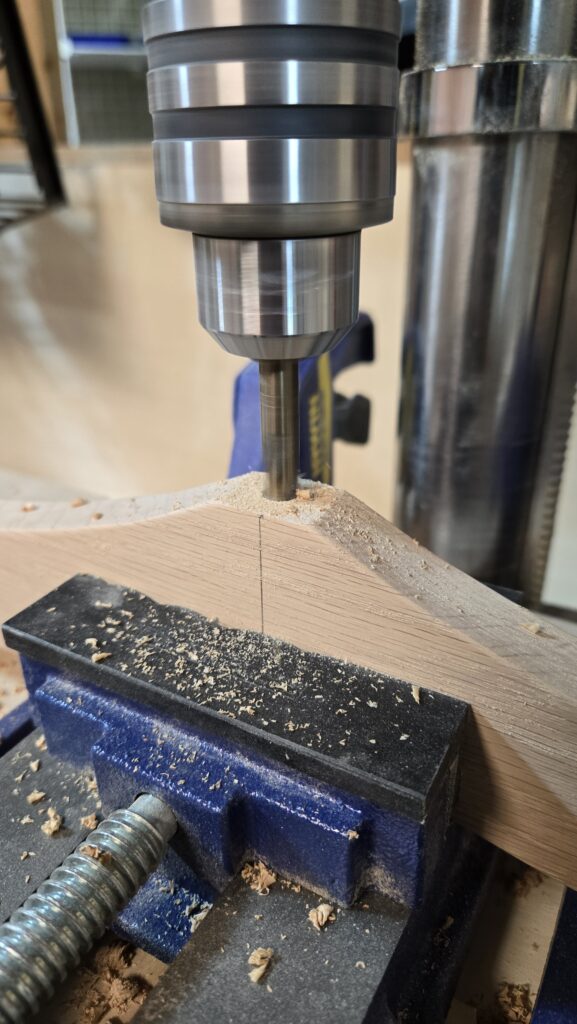 Photo of a drill putting a hole into the centre of a branch of a wooden tree.